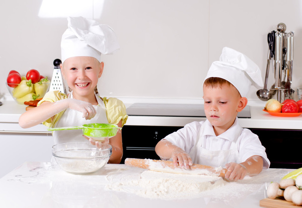 twee gelukkige jonge kinderen leren om te bakken - Foto, afbeelding