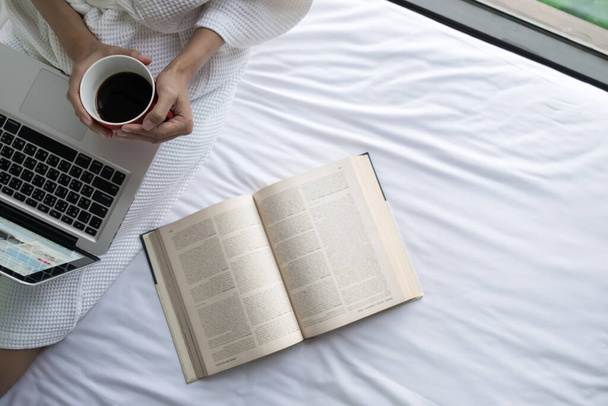Soft photo of woman on the bed with old book and cup of coffee and copy space. - Φωτογραφία, εικόνα
