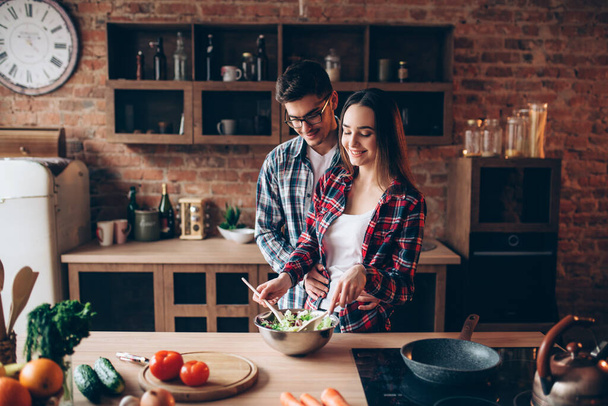 Love couple cooking on the kitchen, vegetable salad preparation. Fresh diet food. Man and woman prepares romantic dinner - Fotó, kép
