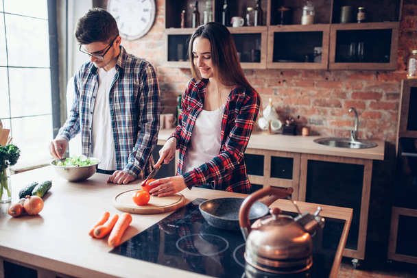 Vrouw en man koken verse groentesalade in kom op de keuken. Voedselbereiding. Paar bereidt romantisch diner, gezonde levensstijl - Foto, afbeelding