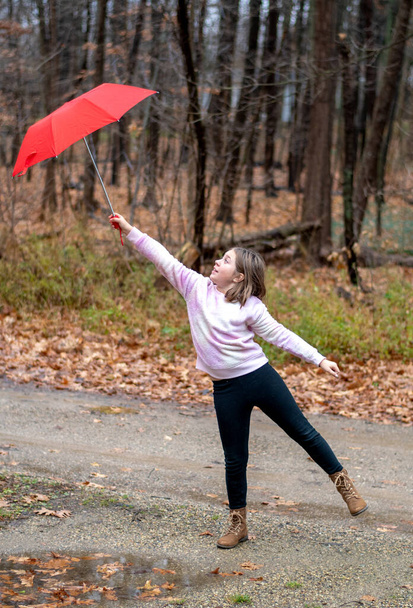 Jovem luta para segurar um guarda-chuva vermelho em um dia ventoso - Foto, Imagem