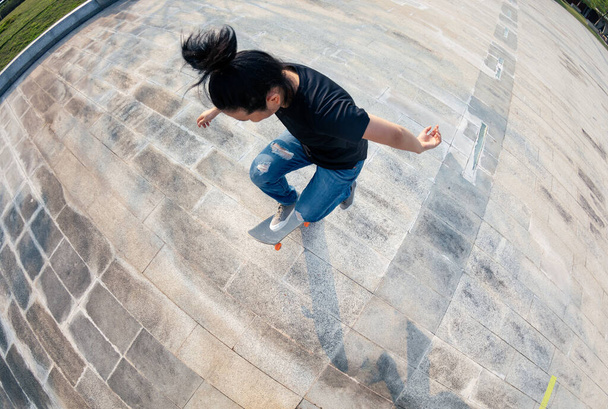 Asian woman skateboarder skateboarding in modern city - Fotoğraf, Görsel