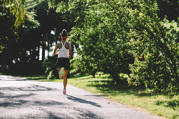 Fitness woman running on sunny tropical park trail - Fotografie, Obrázek