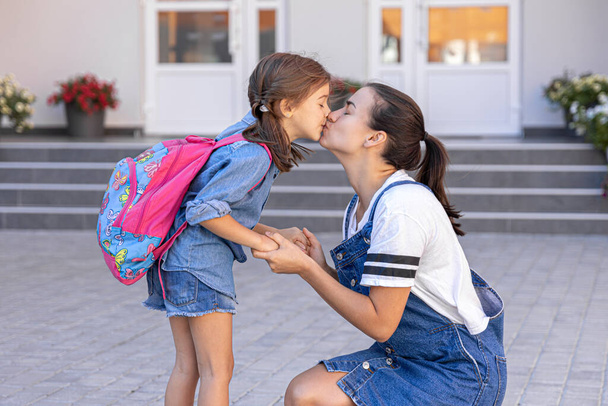 Мать сопровождает ученика в школу, счастливая маленькая девочка с заботливой мамой, вернуться в школу. - Фото, изображение