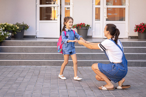 Una madre accompagna lo studente a scuola, una bambina felice con una mamma premurosa, torna a scuola. - Foto, immagini