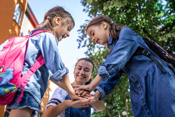 Una mujer joven apoya moralmente a las hijas tomadas de la mano alienta a los niños, la madre acompaña a los estudiantes a la escuela. - Foto, imagen