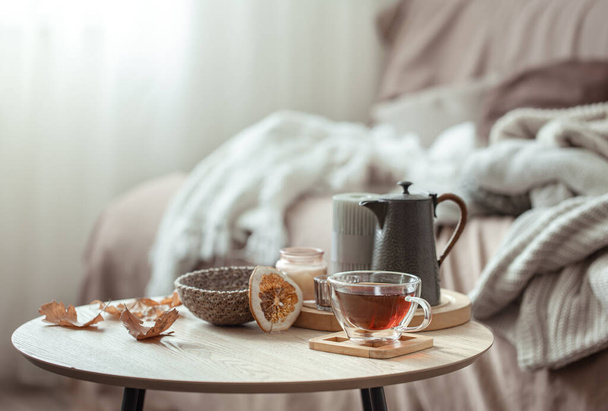 Herbstliche Komposition mit einer Tasse Tee, einer Teekanne und herbstlichen Dekorationsdetails auf verschwommenem Hintergrund. - Foto, Bild