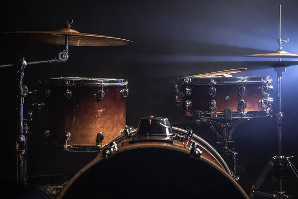 Deel van een drumstel tegen een zwarte achtergrond, percussie-instrument, snaredrum, basdrum, hi-hat op het podium onder de schijnwerpers. - Foto, afbeelding