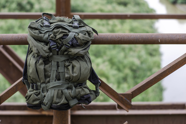 tourist backpack hanging on the railing of the old iron bridge over the river concept tourism travel. High quality photo - Fotografie, Obrázek