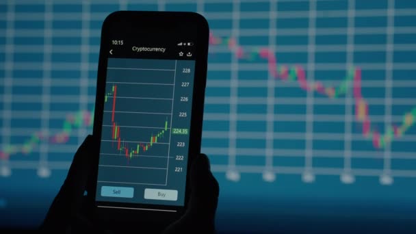 професійний брокер дивиться на детальний графік зміни цін на криптовалюту на екрані мобільного телефону на тлі інших графіків фондової біржі
 - Кадри, відео