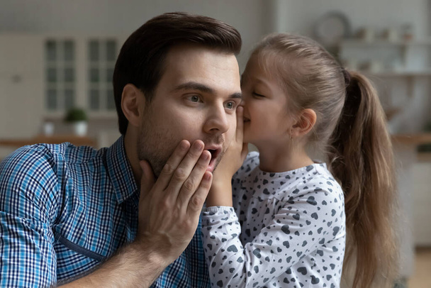 Cute daughter girl telling secret to excited surprised dad - Photo, Image
