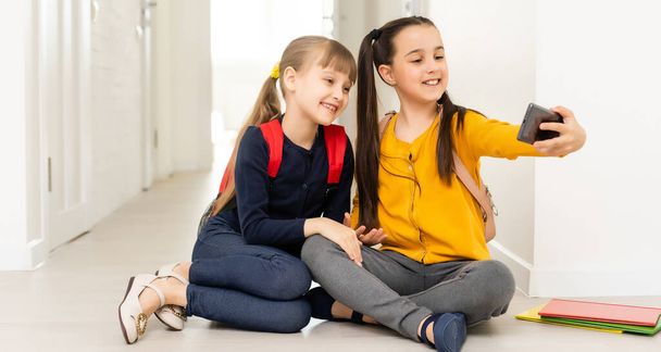 emberek, gyerekek, technológia, barátok és barátság koncepció - boldog kislányok okostelefonnal otthon a padlón - Fotó, kép