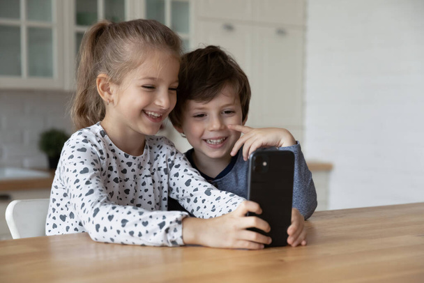Happy excited sibling gen Z kids using smartphone together - Photo, image