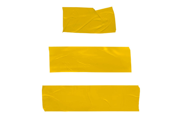Set van geelgouden gescheurde stukken whiskytape op een witte achtergrond. Gescheurde horizontale en verschillende grootte geel plakband, kleverige stukken - Foto, afbeelding
