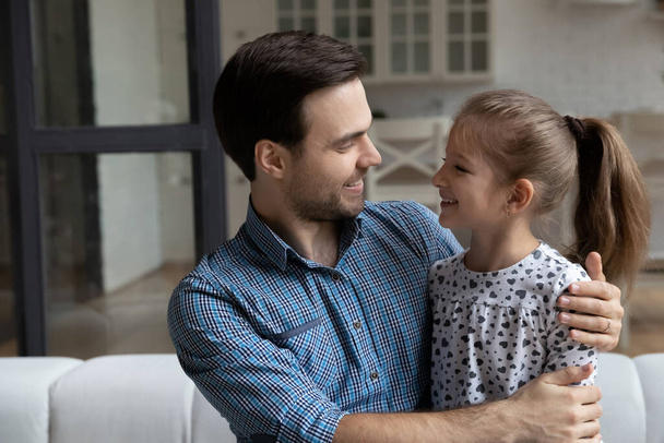 Happy millennial affectionate daddy hugging daughter girl with love - Photo, Image
