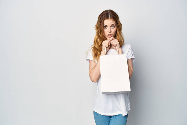 nő egy fehér póló egy csomag a kezében ajándék Bevásárló fény háttér - Fotó, kép