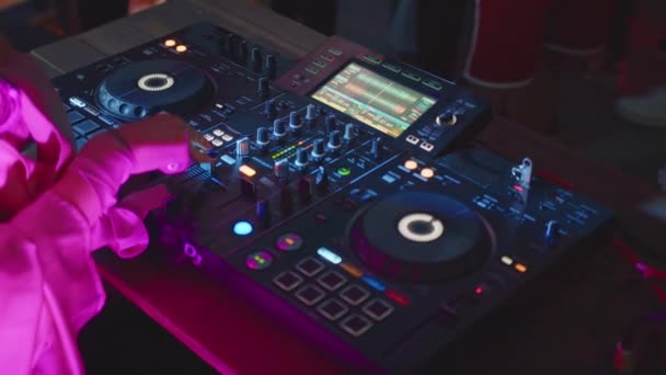 DJの手はディスコクラブで音楽を混合するためのサウンドコンソールを制御します。スローモーションで閉じます。指タッチボタンスライダー、デッキで電子音楽を再生します。ナイトクラブダンスパーティーでのカラーライトショー. - 映像、動画