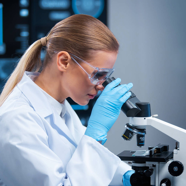 Female doctor works in a modern scientific laboratory using equipment and computer technologies. The scientist does research and develops new vaccines. Science and healthcare concept. - Foto, Bild