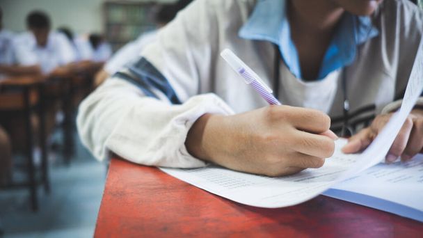 Los estudiantes que escriben y leen el examen responden a las hojas de ejercicios en el aula de la escuela con estrés - Foto, Imagen