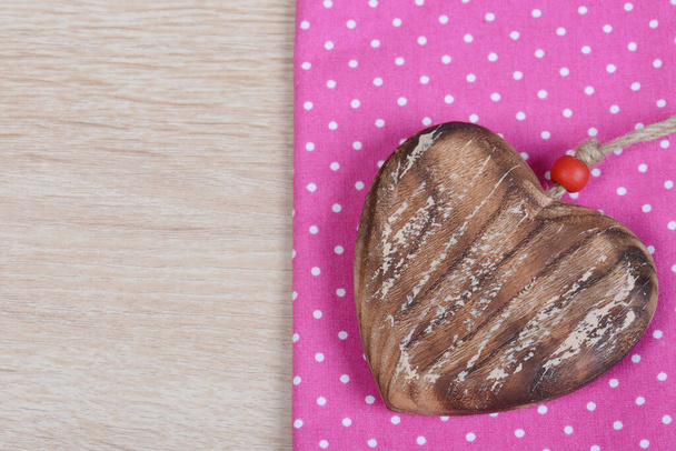 Ένα κολιέ σε σχήμα καρδιάς σε ένα μωβ χαρτί σε μια καφέ επιφάνεια τραπεζιού - Φωτογραφία, εικόνα