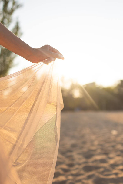 fille posant dans une robe transparente au coucher du soleil. promenades le long de la plage le soir - Photo, image
