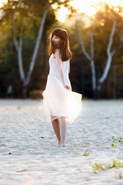 belle jeune femme à la mode en robe élégante marchant à la plage au coucher du soleil
 - Photo, image