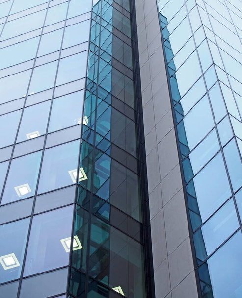 Nahaufnahme eines modernen Bürogebäudes mit geometrischen Glaspaneelen, beleuchtet mit quadratischen Lichtern - Foto, Bild