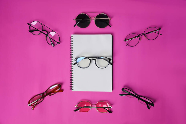 Empty notebook and sunglasses on pink background. - Foto, Imagen