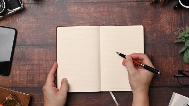 Nad pohled žena držící pero psaní na prázdný notebook. - Fotografie, Obrázek