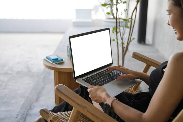 Πλευρική άποψη χαρούμενη νεαρή γυναίκα κάθεται σε cafe και surfing internet με φορητό υπολογιστή. - Φωτογραφία, εικόνα