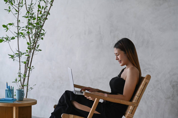 Вид збоку приваблива молода жінка використовує ноутбук у кафе
. - Фото, зображення