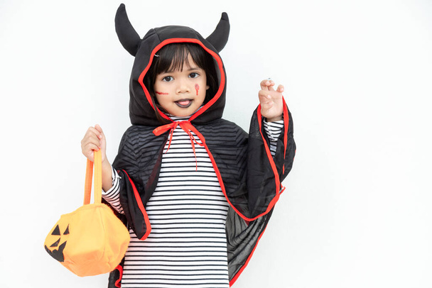 Забавная идея Хэллоуина ребенка, маленькая милая девочка с костюмом Хэллоуин призрак страшно он держит оранжевый призрак тыквы на руке, на белом фоне - Фото, изображение