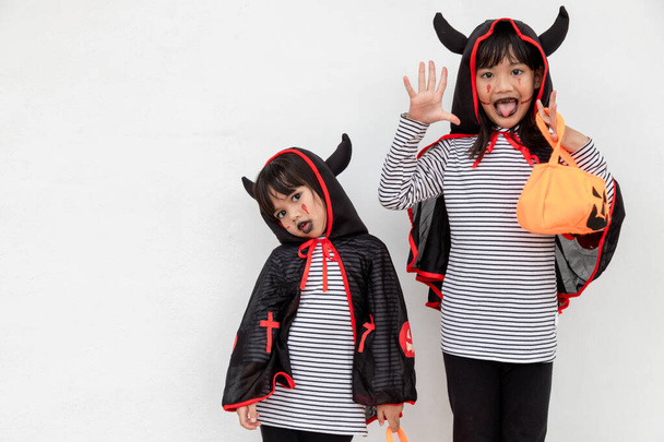 Feliz Halloween! dos niños en disfraces de Halloween y con calabazas sobre fondo blanco - Foto, imagen