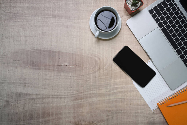 Ordenador portátil, teléfono inteligente y taza de café en escritorio de madera. - Foto, imagen