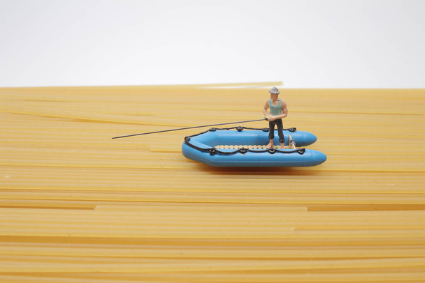 η μικροσκοπική φιγούρα με το μικρό σκάφος και το ψάρεμα - Φωτογραφία, εικόνα