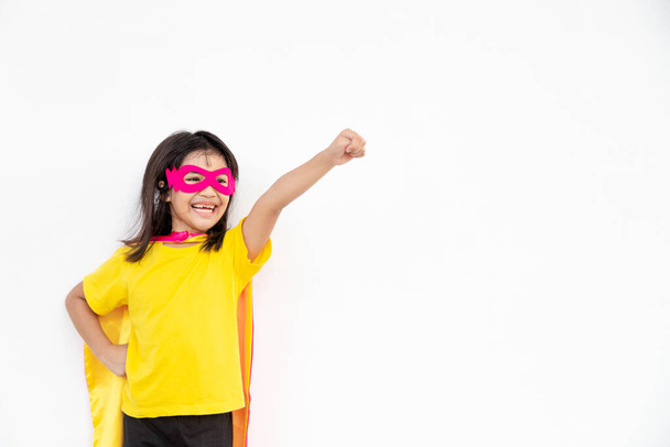 Kinderkonzept, lächelndes Mädchen, das Superheldin auf weißem Hintergrund spielt - Foto, Bild