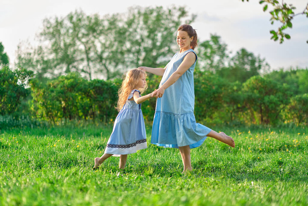 Naturszene mit familiärem Outdoor-Lifestyle. Mutter und kleine Tochter spielen zusammen in einem Park. Glückliches Familienkonzept. Glück und Harmonie im Familienleben. - Foto, Bild