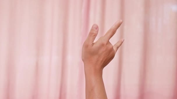 Hände machen I Love You Symbol auf rosa Hintergrund. Frauenhände sagen "Ich liebe dich" in Gebärdensprache. Valentinstag. - Filmmaterial, Video