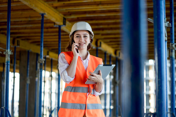 Female construction engineer. Architect with a tablet computer at a construction site. Young Woman looking, building site place on background. Construction concept. - Foto, afbeelding