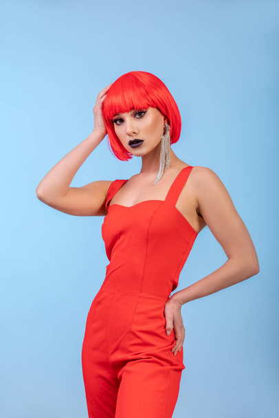Portrait of beautiful sexy woman in red wig on blue background. - Zdjęcie, obraz