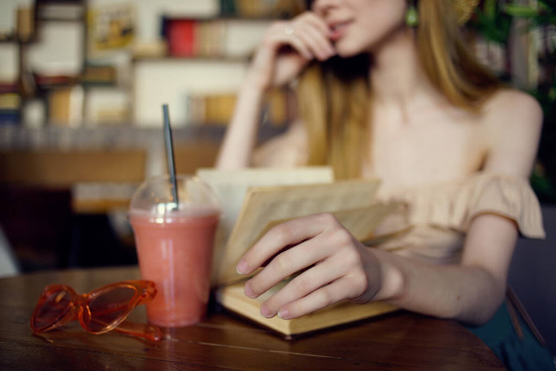 Χαρούμενη γυναίκα κάθεται σε ένα τραπέζι με ένα ποτό σε ένα καφέ αναψυχής - Φωτογραφία, εικόνα