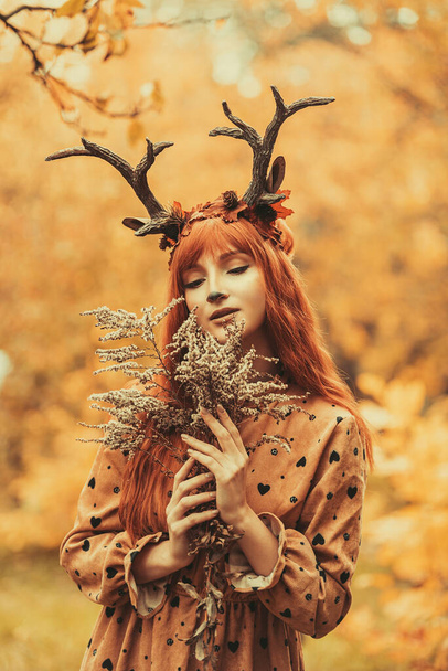 fairy woman with deer horns in autumn forest. Face painting. Beautiful mystery woman. redhead girl with big eyes magical sight - Фото, изображение