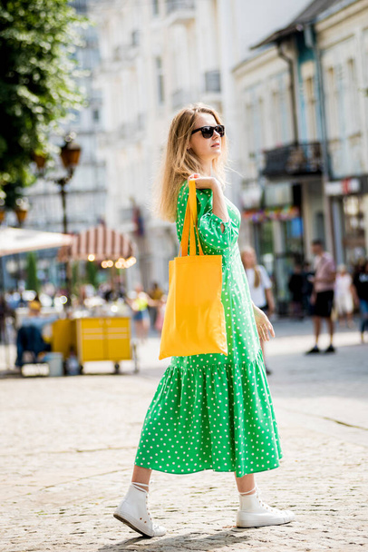 Young beautyful woman with yellow linen eco bag on city background. - Zdjęcie, obraz