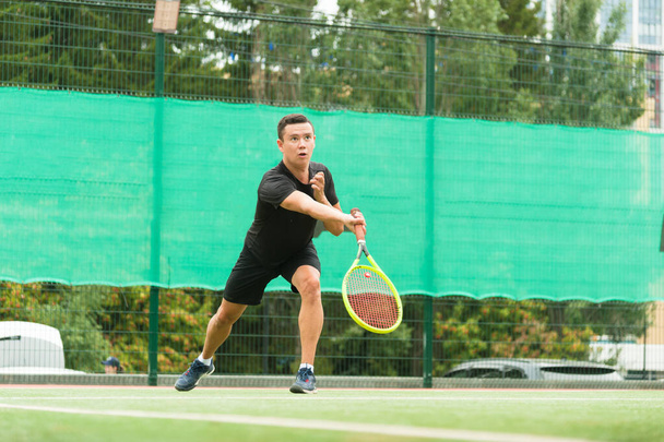 Ein männlicher Tennisspieler schlägt elegant einen Tennisball. Ein Tennisspieler, der aussieht wie ein Tänzer. - Foto, Bild