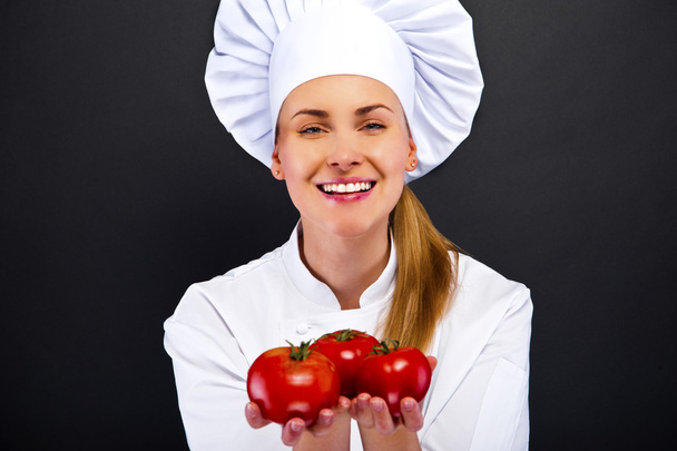 Portret van een jonge vrouw chef-kok met tomaten  - Foto, afbeelding