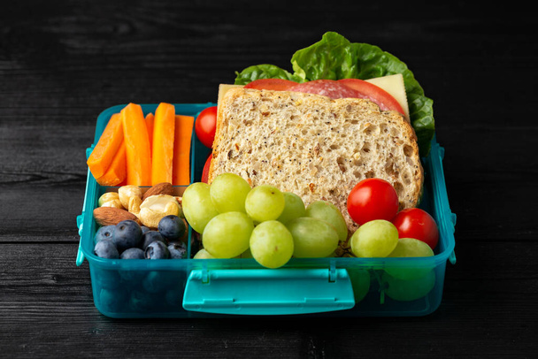 Escuela saludable, almuerzo de trabajo con sándwiches y verduras frescas, nueces y frutas en mesa de madera - Foto, Imagen