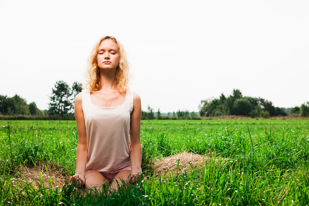 Beautiful woman meditating in summer park - Фото, зображення
