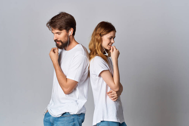 alegre joven pareja en blanco camisetas con auriculares escuchando música alegría amistad - Foto, imagen