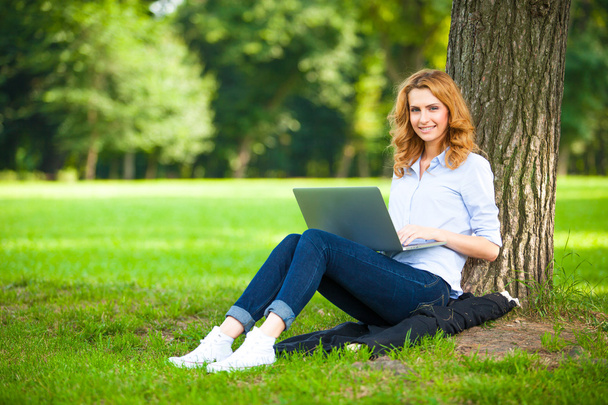 dizüstü bilgisayar ile parkta oturan güzel kadın - Fotoğraf, Görsel