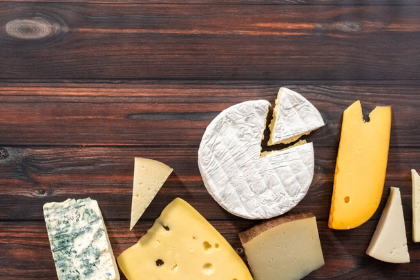 Pose plate. Variété de grandes cales de fromage gastronomique sur fond de bois foncé. - Photo, image